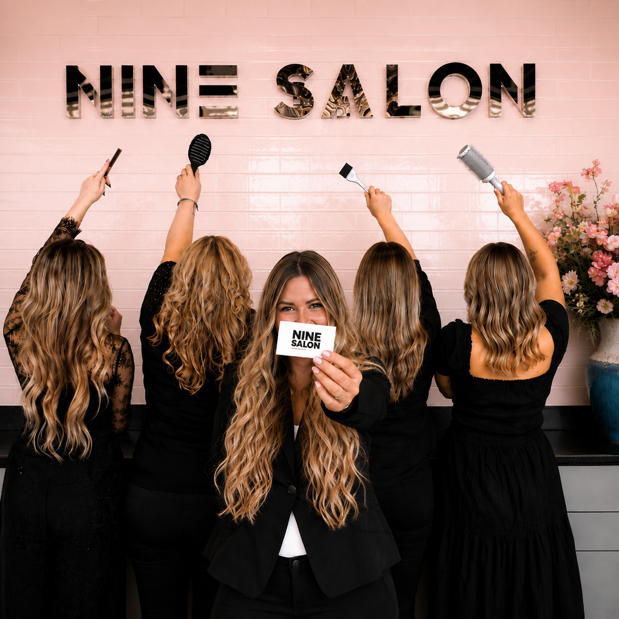 The Nine Salon team in front of the salon's signature wall